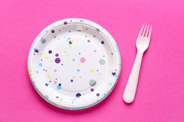 Pembe arka planda tek kullanımlık kağıt ve çatal.