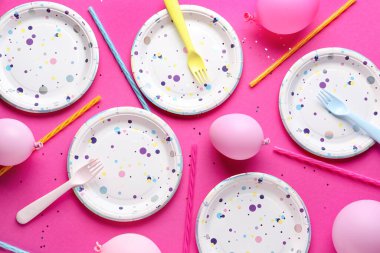 Masa ayarları kağıt sofra takımı ve pembe arka planda balonlar