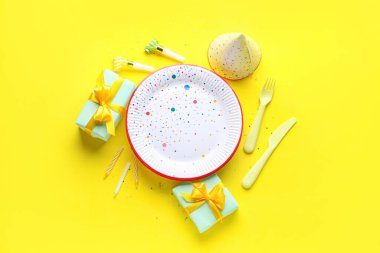 Sarı arka planda farklı parti dekorasyonu olan tek kullanımlık kağıt tabak.