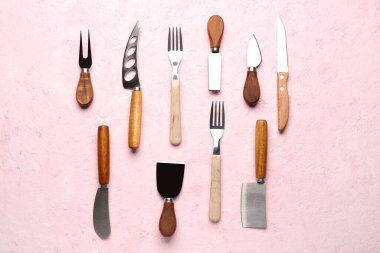 Pembe arka planda farklı çatal ve bıçaklar.