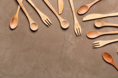 Kahverengi arka planda tahta çatallar, bıçaklar ve kaşıklar.