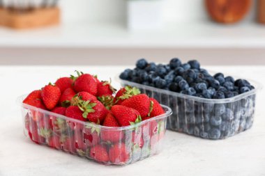 Mutfaktaki masada olgun böğürtlenli plastik kaplar.