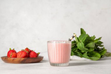 Hafif arka planda bir bardak lezzetli çilekli smoothie.