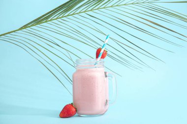 Mason kavanozu mavi arka planda lezzetli çilekli smoothie.