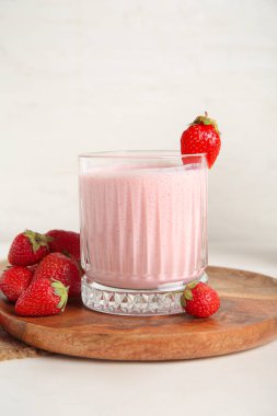 Hafif arka planda bir bardak lezzetli çilekli smoothie.