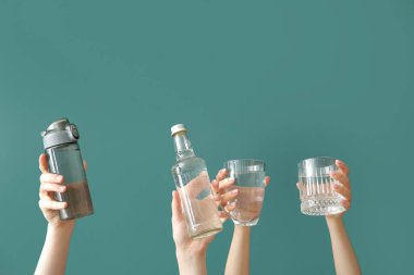 Şişeli kadın elleri ve yeşil arka planda soğuk su bardakları.