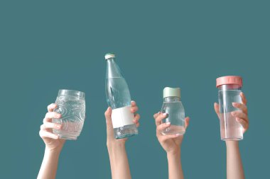 Şişeli kadın elleri ve yeşil arka planda bir bardak soğuk su.