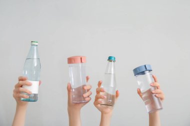 Arka planda soğuk su şişeleri olan kadın eller.