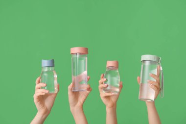 Yeşil arka planda soğuk su şişeleri olan kadın eller.