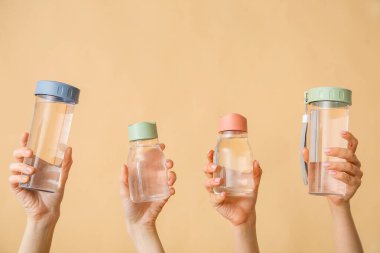 Bej arka planda soğuk su şişeleri olan kadın eller.