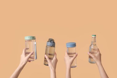 Bej arka planda soğuk su şişeleri olan kadın eller.