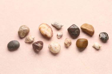 Pembe arka planda birçok çakıl taşı ve deniz kabuğu var.