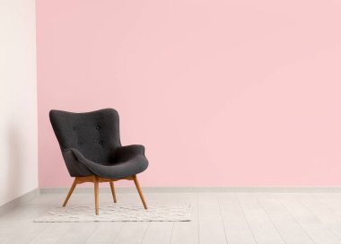 Pembe duvarın yanındaki gri koltuk