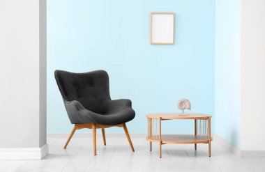Mavi duvarın yanında dekoru olan gri koltuk ve kahve masası
