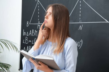 Sınıfta tahtaya yakın bir kitapla matematik öğretmenini düşünmek.