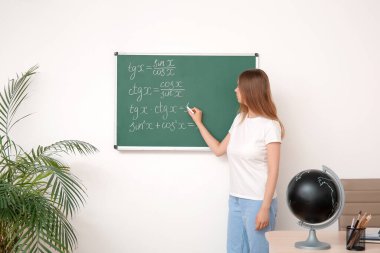 Sınıfta tahtaya yazı yazan genç matematik öğretmeni.