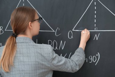 Sınıfta tahtaya yazı yazan genç matematik öğretmeni.