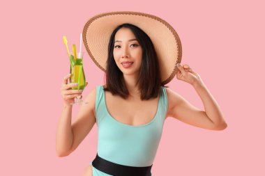 Mayo giymiş güzel bir Asyalı kadın ve pembe arka planda Mojito kokteyli.