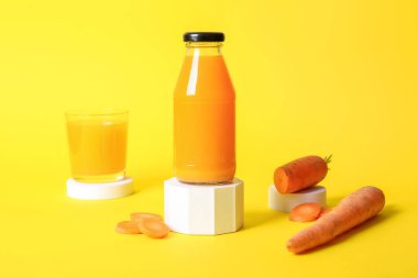 Süslü podyumlar ve sarı arka planda bir bardak taze havuç suyu.