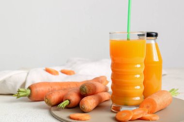 Beyaz arka planda bardak ve bir şişe taze havuç suyu.