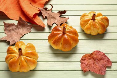 Yeşil ahşap arka planda lezzetli balkabağı şekilli çörekler