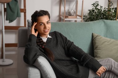 Genç esmer kadın evdeki kanepede uzanıyor.