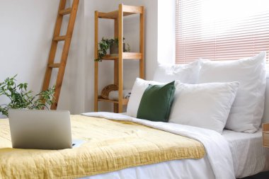 Yastıklı ve laptoplu büyük yatak şık bir odada.