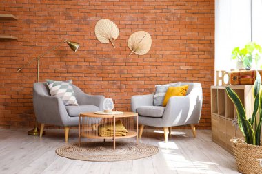 Şık gri koltuklar, sehpa ve açık oturma odasındaki pencerenin yanındaki raf ünitesi.