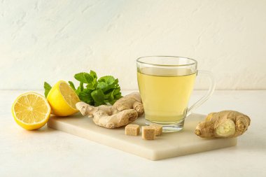 Beyaz arka planda limon ve nane aromalı bir bardak zencefil çayı.