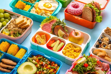 Mavi arka planda farklı lezzetli yemekleri olan bir sürü beslenme çantası.