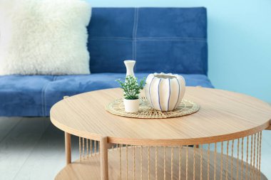 Dekorlu ahşap sehpa ve mavi duvarın yanındaki kanepe.