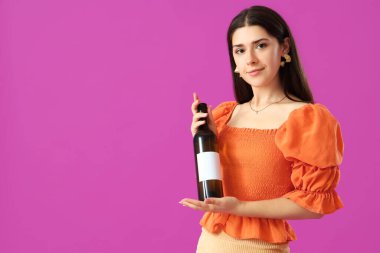 Mor arka planda şarap şişesi olan genç bir kadın.