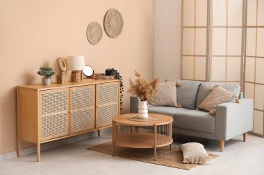 Hasır halılı oturma odası, kahve masasında otlar ve gri kanepe.