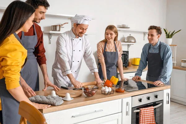 意大利厨师和一群年轻人在厨房烹饪课上准备披萨 — 图库照片