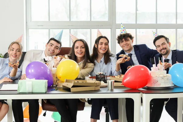 Group of business people eating pizza at birthday party in office