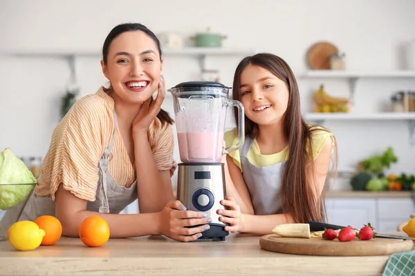 Küçük kız ve annesi mutfakta blender ile smoothie yapıyorlar.