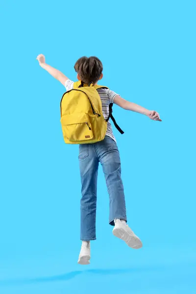 Springender Kleiner Junge Mit Schulranzen Auf Blauem Hintergrund Rückseite — Stockfoto