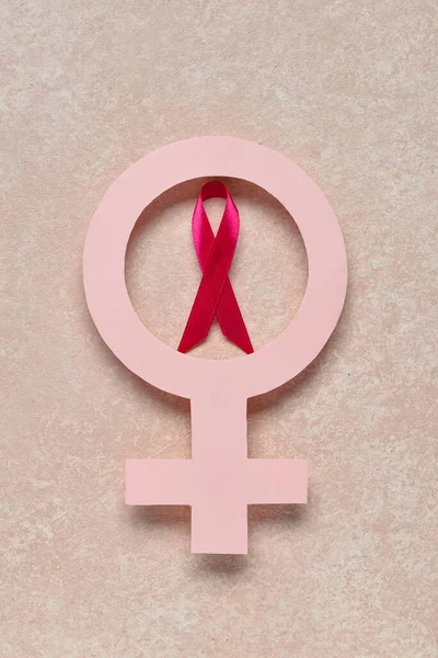 Pink awareness ribbon and paper female gender symbol on color background. Breast cancer concept