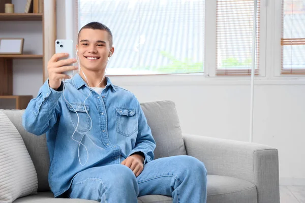 Young man with mobile phone video chatting at home