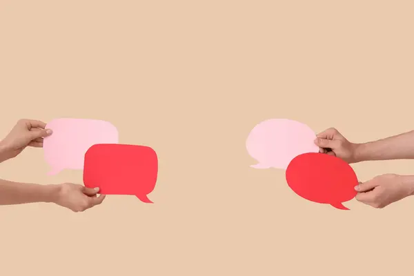 Different hands with speech bubbles on beige background