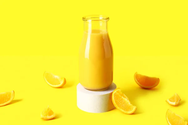 Dekoratives Podium Mit Einer Flasche Frischem Orangensaft Auf Gelbem Hintergrund — Stockfoto