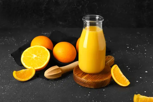 Holzbrett Mit Flasche Frischem Orangensaft Und Saftpresse Auf Schwarzem Hintergrund — Stockfoto