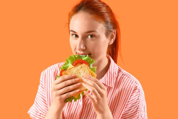 Giovane Donna Rossa Mangiare Gustoso Panino Sfondo Arancione Primo Piano — Foto Stock
