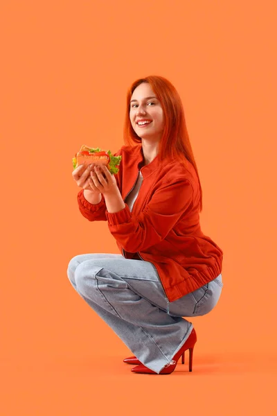 Giovane Donna Rossa Con Gustoso Panino Sfondo Arancione — Foto Stock