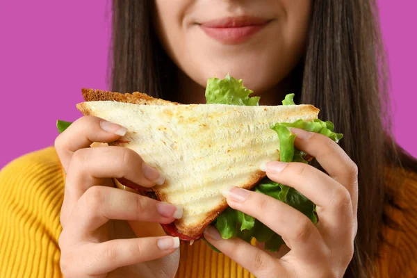 紫色の背景でおいしいサンドイッチを持つ若い女性 クローズアップ — ストック写真