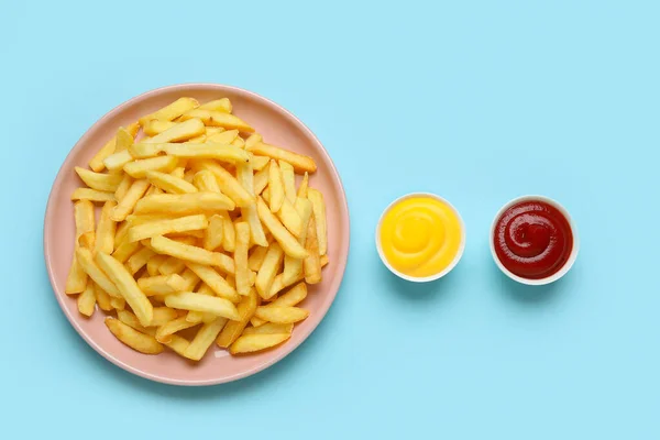 stock image Plate with golden french fries, ketchup and cheese sauce on blue background