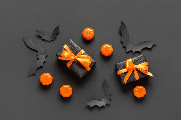Gift boxes with pumpkins and paper bats for Halloween celebration on black background
