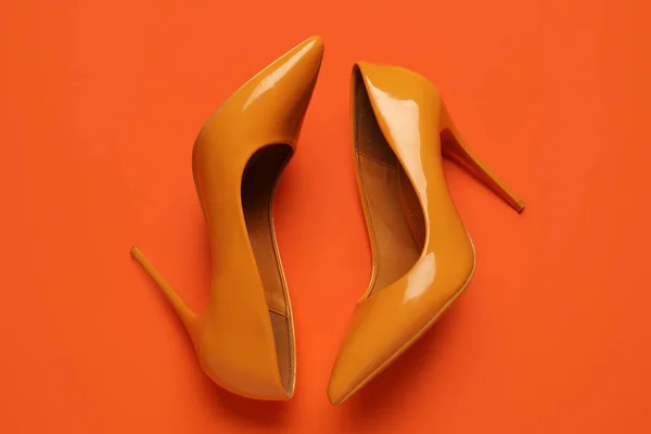 Stylish yellow high heels on orange background