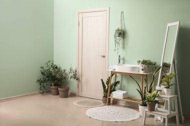 Lavabosu, aynası ve çiçekleri olan banyonun içi.