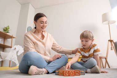 Dadı ve küçük çocuk evde küplerle oynuyorlar.